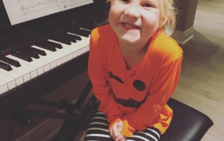 Very happy young piano student sitting in front of piano