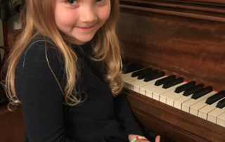 Child at piano smiling for camera during paino lesson