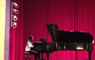 Piano student playing piano on stage at recital