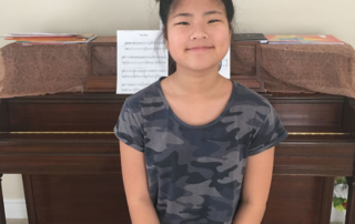 Smiling student sitting in front of piano