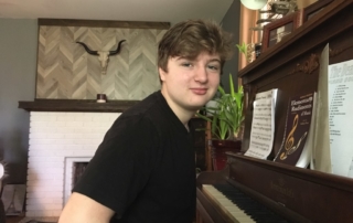 Piano student sitting at paino and smiling at camera