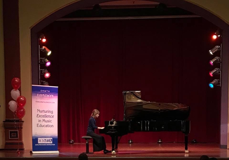 Piano student playing piano on stage at recital