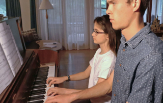 Piano teacher and student playing piano during lesson